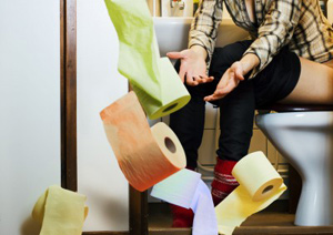 Woman on toilet being bombarded with toilet rolls