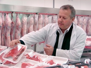 A butcher setting out chops wrapped in styrofoam trays and clingfilm