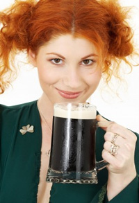 A young Irishwoman holds up a pint of stout to the camera