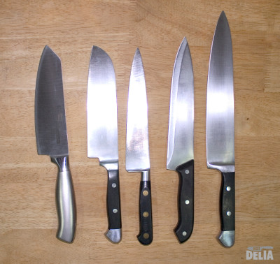 Five chef's knives displayed on a wooden work table