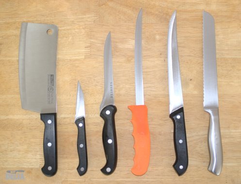 A variety of kitchen knives displayed on a wooden table