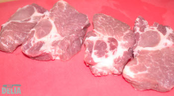 Pieces of pork collar on a red chopping board
