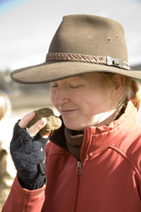 A woman holds a black truffle and breathes in the aroma appreciatively
