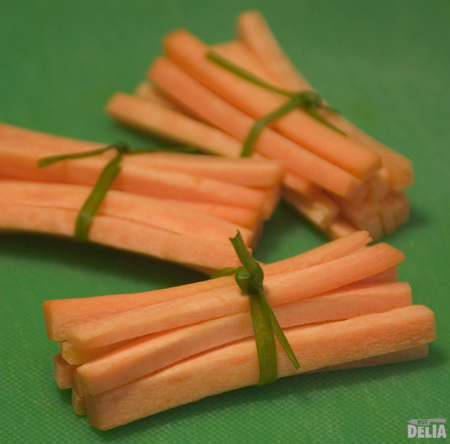 Julienne-cut carrots tied into little bundles with spring onion green shoots