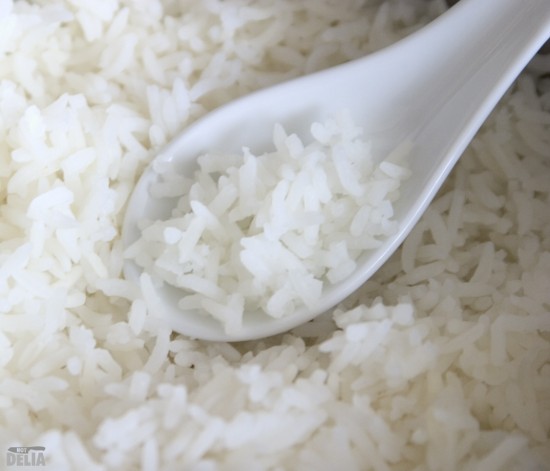 Steamed rice in a Chinese soup spoon on a bed of... steamed rice