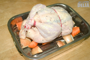Chicken buttered up and trussed with stretchy silicone bands ready for roasting