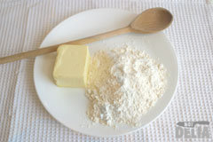 Roux ingredients - flour and butter - on a dinner plate, together with a wooden spoon