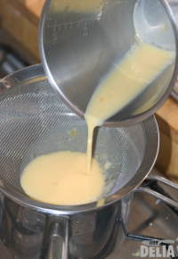 Eggs being passed through a fine sieve into a saucepan