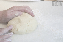 A ball of pastry on a floured white food preparation board