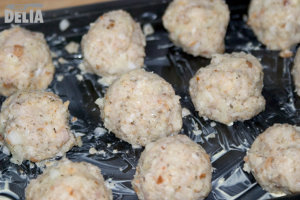 Raw sage and onion stuffing balls on a baking tray ready for cooking