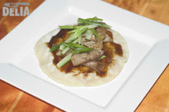 A Chinese pancake spread with hoisin sauce and loaded with pork strips and julienne spring onions and cucumber