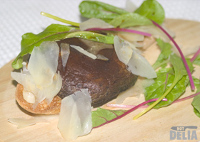 Bruschetta with Portobello mushrooms, served on a wooden platter with leaves, Parmesan shavings and balsamic dressing