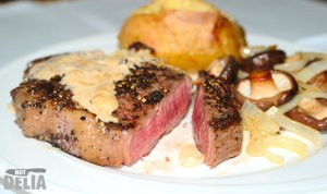 Rib eye steak cooked medium rare with a baked potato and mushrooms