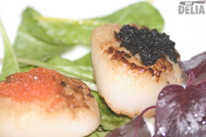 Seared scallops with butter and garlic on a bed of leaves