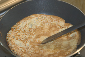 A flipped pancake cooking in a small frying-pan