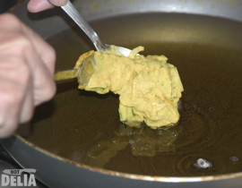 A test onion bhaji is spooned into hot oil in a wok