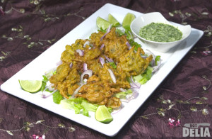 Bhajis on a plate with a small dish of coriander and coconut dip