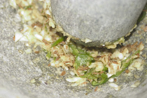 Ground garlic, green chillies and cumin in a mortar