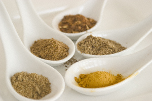 Cumin, coriander, red chilli, garam masala and turmeric powders presented in Chinese soup spoons on a plate