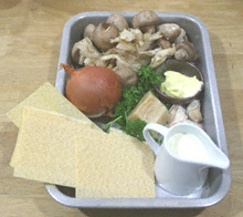 Mushrooms, onions, sheets of lasagne, a small jug of milk, butter, Parmesan cheese and parsley in an aluminium roasting tin