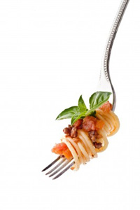 A forkful of spaghetti bolognese on a fork, garnished with a tiny sprig of basil
