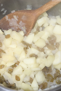 Apples, onions and sultanas cooking together in a saucepan