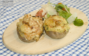 Two twice-baked potatoes with two different fillings on a wooden platter