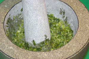 Thai green curry paste being mashed in a Thai stone mortar and pestle