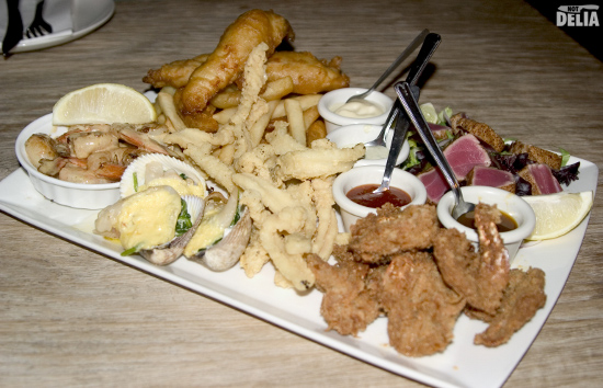 A seafood platter with various fish, shellfish, chips and dips