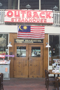 Doorway and signage for the Outback Steakhouse, with some tables and chairs