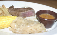 Cold (and undercooked) steak, frozen fries, watery peppercorn sauce (no peppercorns in evidence), pale, greasy onions and corn-on-the-cob on a white plate