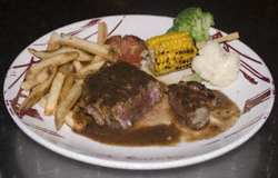 Medium rare steak with corn-on-the-cob, chips, broccoli, cauliflower and grilled tomato