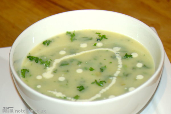Close-up of a bowl of leek and potato soup with extra herbs and a swirl of fresh cream