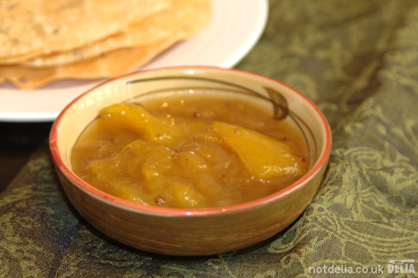 A dish of mango chutney with some poppadoms