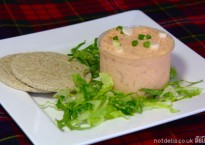 Smoked salmon paté on a plate with oatcakes and shredded lettuce garnish