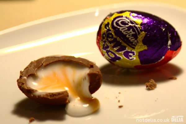 Half a Cadbury Creme Egg next to an unwrapped one